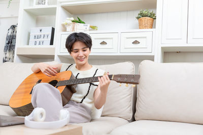 Young woman using laptop while sitting on sofa at home