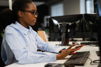 Side view of man using laptop at office