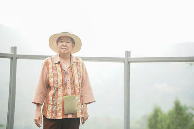 Old elderly female elder woman traveller traveling on footbridge in park. senior leisure lifestyle