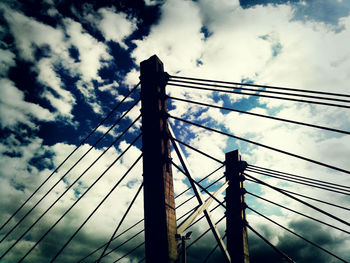 Low angle view of power lines against cloudy sky