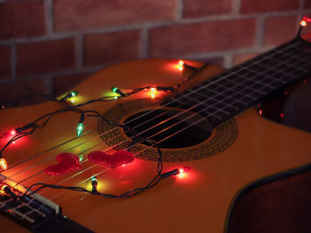 Close-up of heart shape and illuminated multi colored lighting equipment over guitar