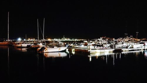 Sailboats moored in harbor at night