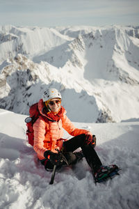 Rear view of woman sitting on snow covered landscape