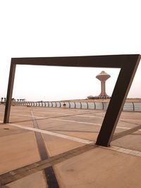 Man by railing against sea against clear sky