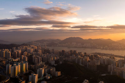 Cityscape by sea against sky during sunset