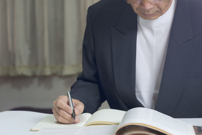 The business man in black suit was taking notes on small notebook.