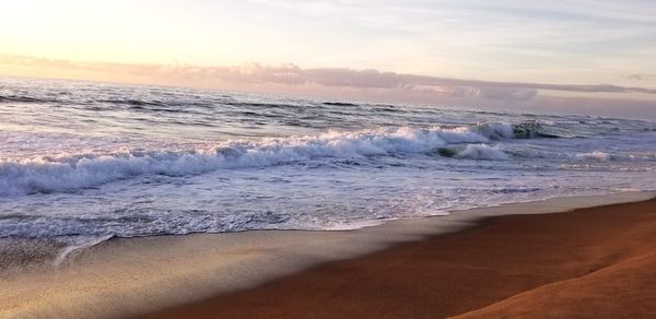 Waves rushing towards shore during sunset