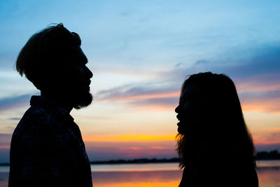 Silhouette man and woman against sky during sunset