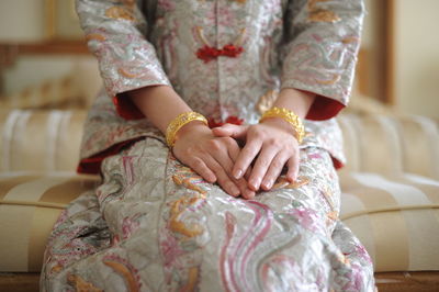 Midsection of woman in traditional clothing sitting on sofa