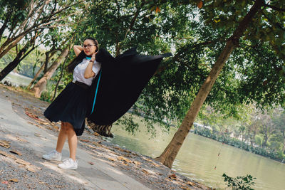 Portrait of young woman while standing against trees