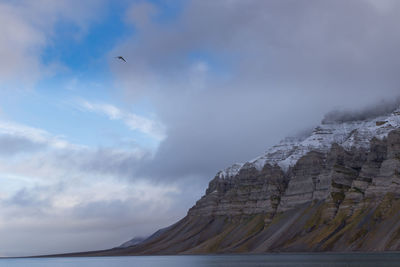 Colorful rocky mountain in svalbard, norway. upper part covered by the first snow in august