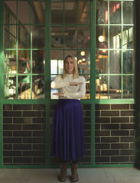 Portrait of smiling young woman standing against illuminated building