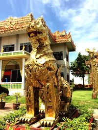 Statue by building against sky