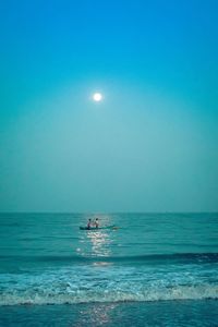 Men in boat on sea against sky at dawn