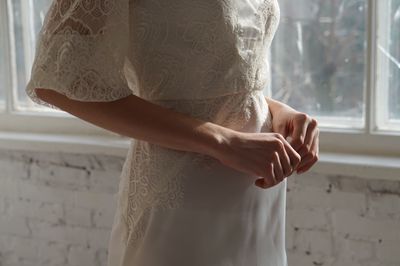 Midsection of bride standing by window at home