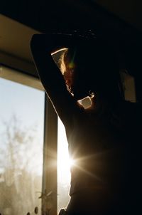 Silhouette young woman by window at home