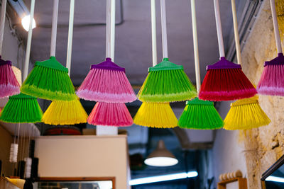 Close-up of multi colored brooms hanging for sale