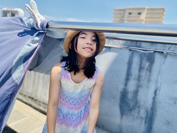 Portrait of young woman standing against wall