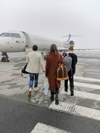 Rear view of women walking on airport runway