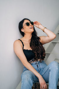 Young woman looking down while sitting against wall