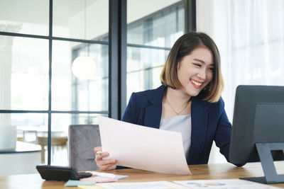 Young woman using phone while sitting on table