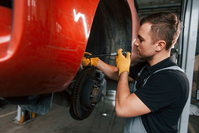 Fixing breaks. man in uniform is working in the auto service.