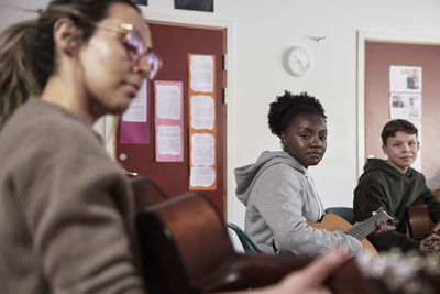 Teenagers attending guitar lesson