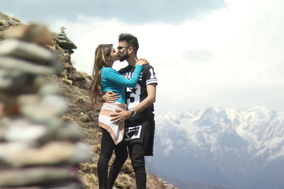 Couple standing on mountain against sky