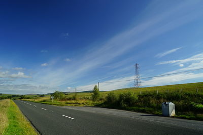 Road by trees against blue sky