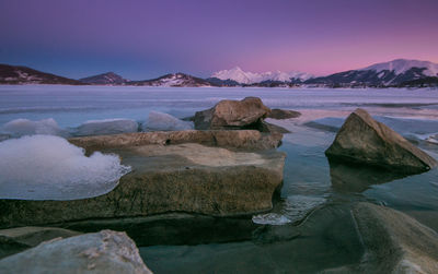 Rocks by sea against sky during sunset in the famous lake of campotosto, abruzzo
