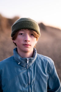 Portrait of teenage boy wearing beenie standing on beach