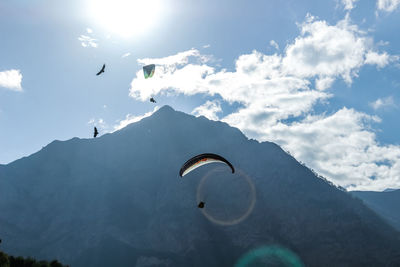 Person paragliding over mountain against sky