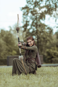 Beautiful archer holding bow and arrow while standing outdoors