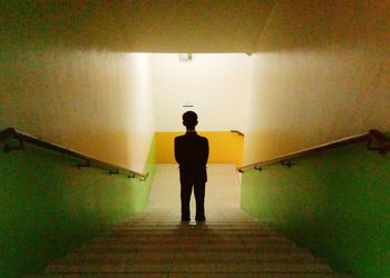 Rear view of man standing on staircase in building