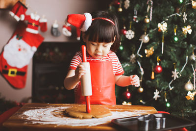 Girl preparing food on table against christmas tree