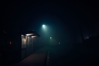 Illuminated street light against building at night