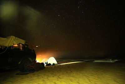 Illuminated tents at campsite against sky at night