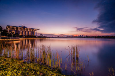 Tuanku mizan zainal abidin mosque by lake against sky at dusk