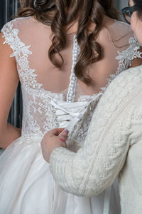 Woman dressing bride during wedding