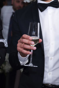 Midsection of man holding wine glass