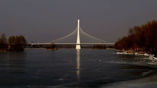 Bridge over river against sky during winter