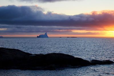 Scenic view of sea against cloudy sky at sunset