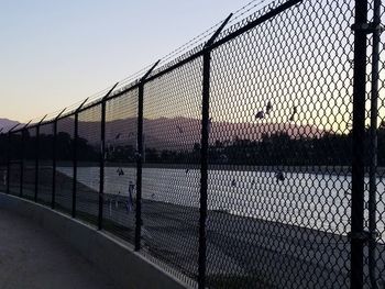 Chainlink fence against sky during sunset