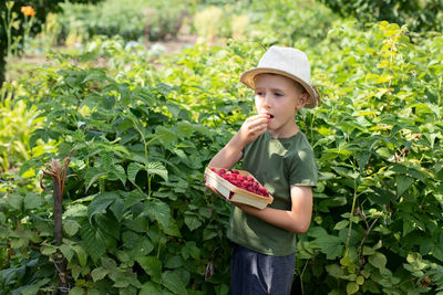 Young woman standing against plants