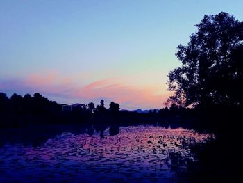 Silhouette trees by lake against sky during sunset
