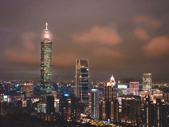 Illuminated buildings in city against sky at night