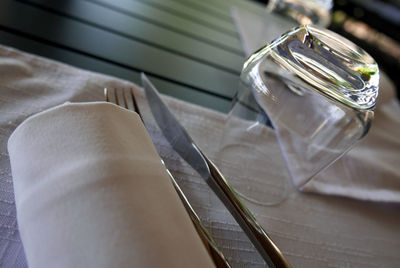 High angle view of napkin and silverware by glass on table at restaurant