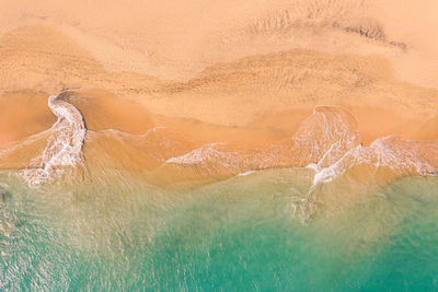 Aerial view of atlantic ocean coast with crystal clear turquoise water, waves rolling into the shore