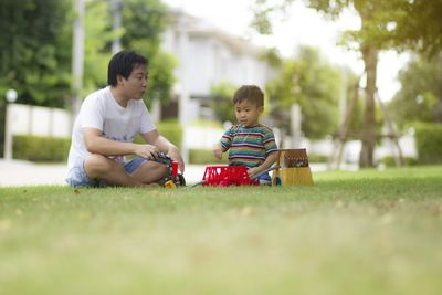 Rear view of boy sitting on grass against plants