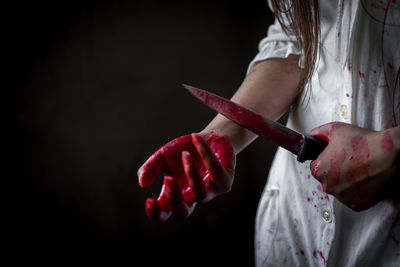 Midsection of evil woman holding knife covered with blood